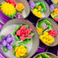 Small candle tin with pink, yellow, and purple flower wax with green leaves