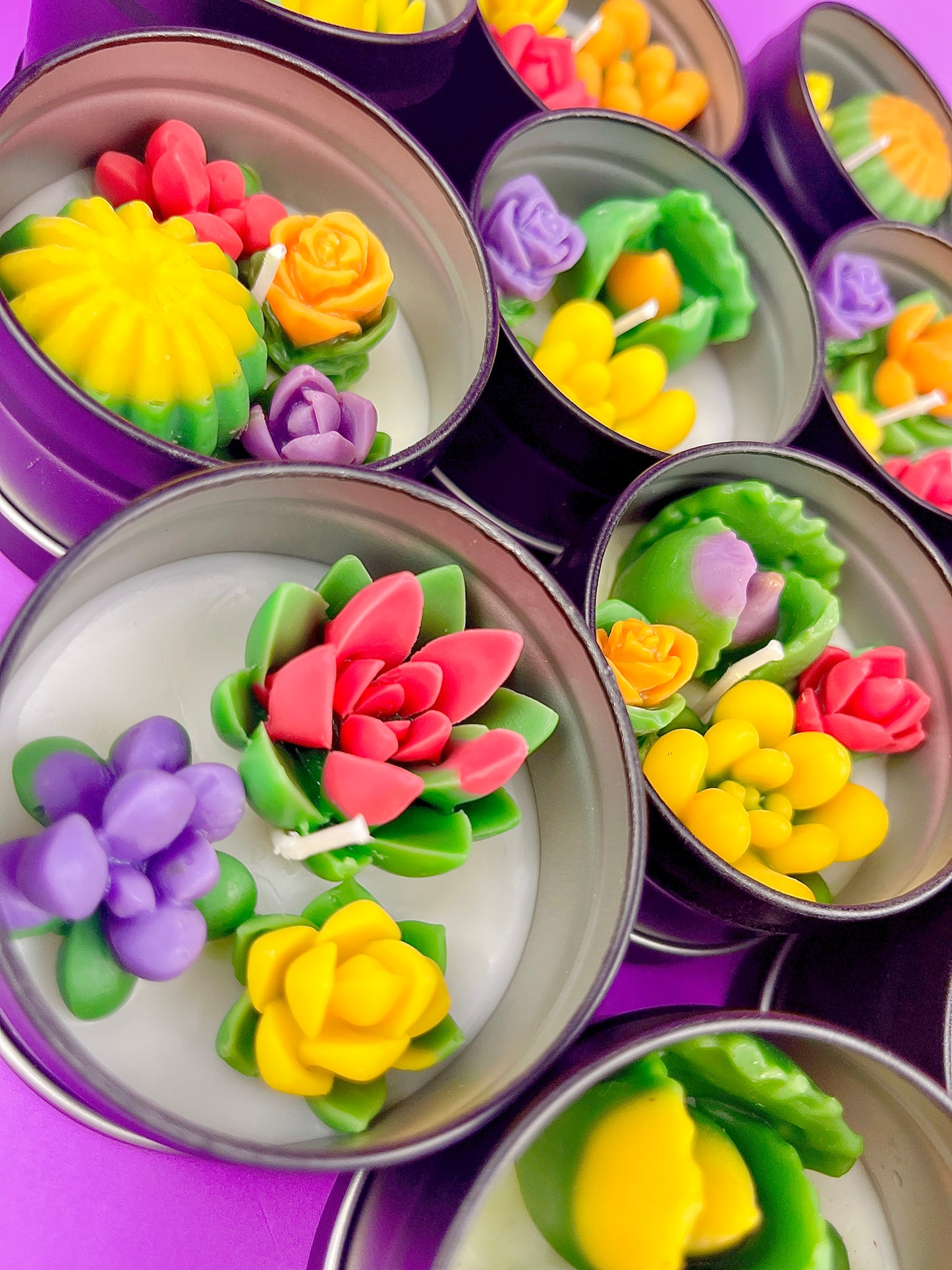 Small candle tin with pink, yellow, and purple flower wax with green leaves