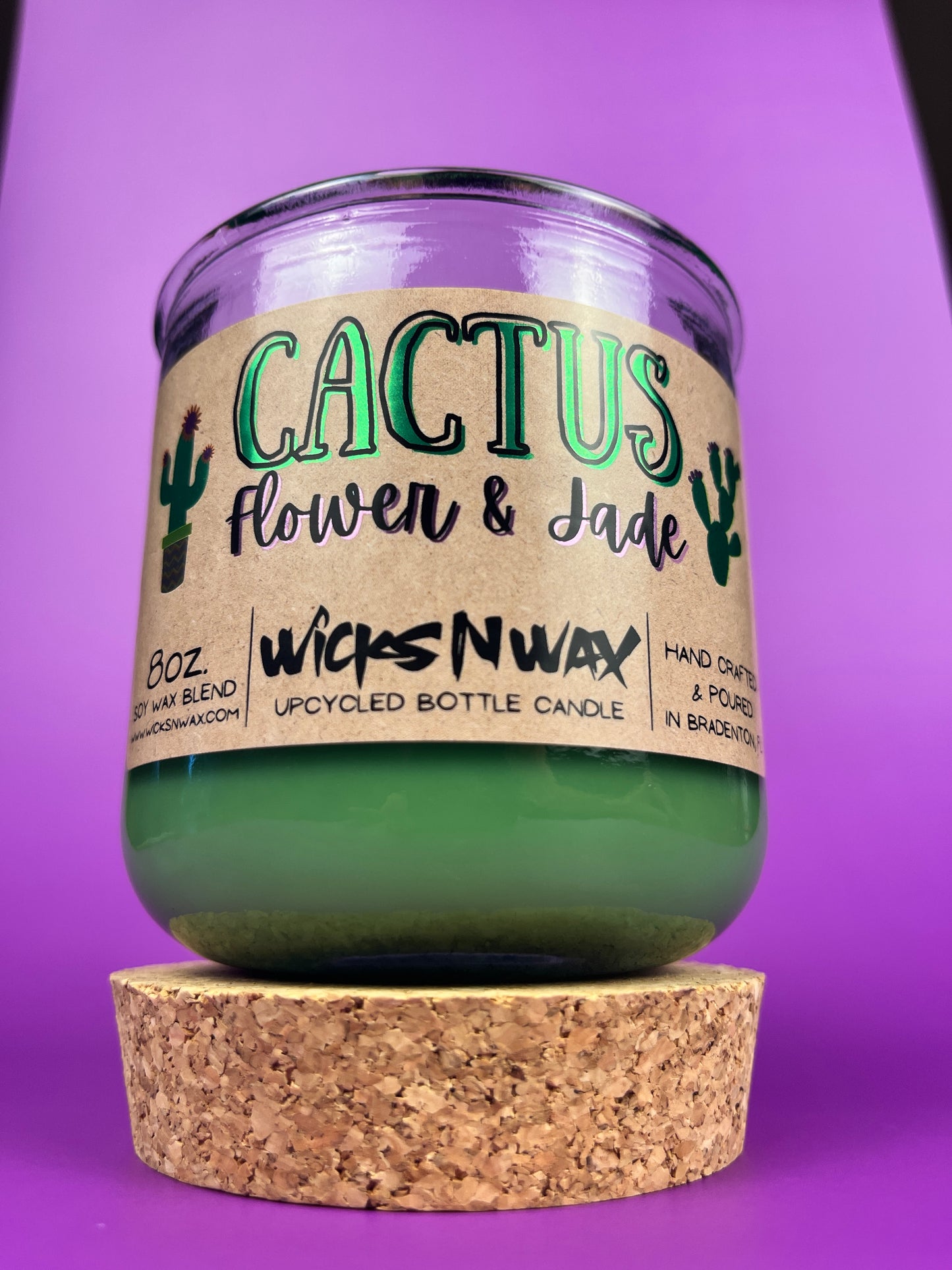 Recycled glass candle jar with green wax and tan cork base, label facing front