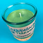 Recycled glass candle with green wax pool and centered wick, Caribbean Teakwood label