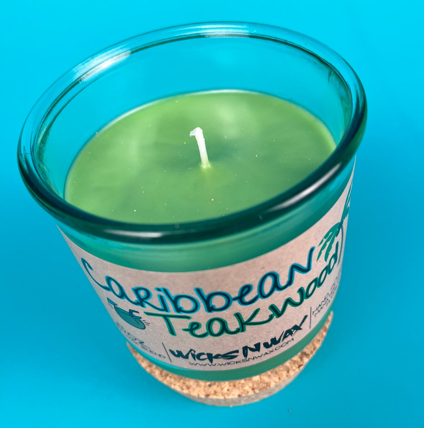Recycled glass candle with green wax pool and centered wick, Caribbean Teakwood label