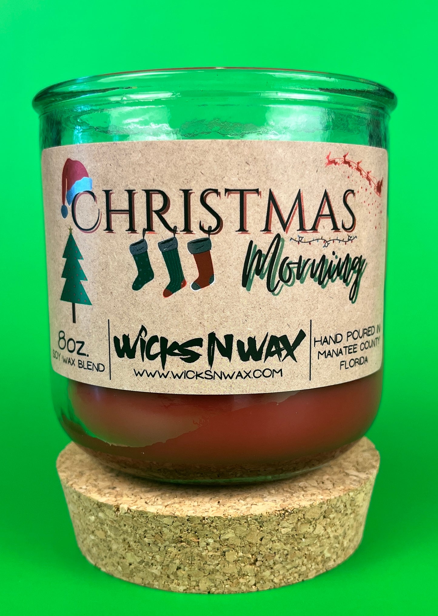 Christmas Morning recycled glass candle with front label and green glass jar, on cork base