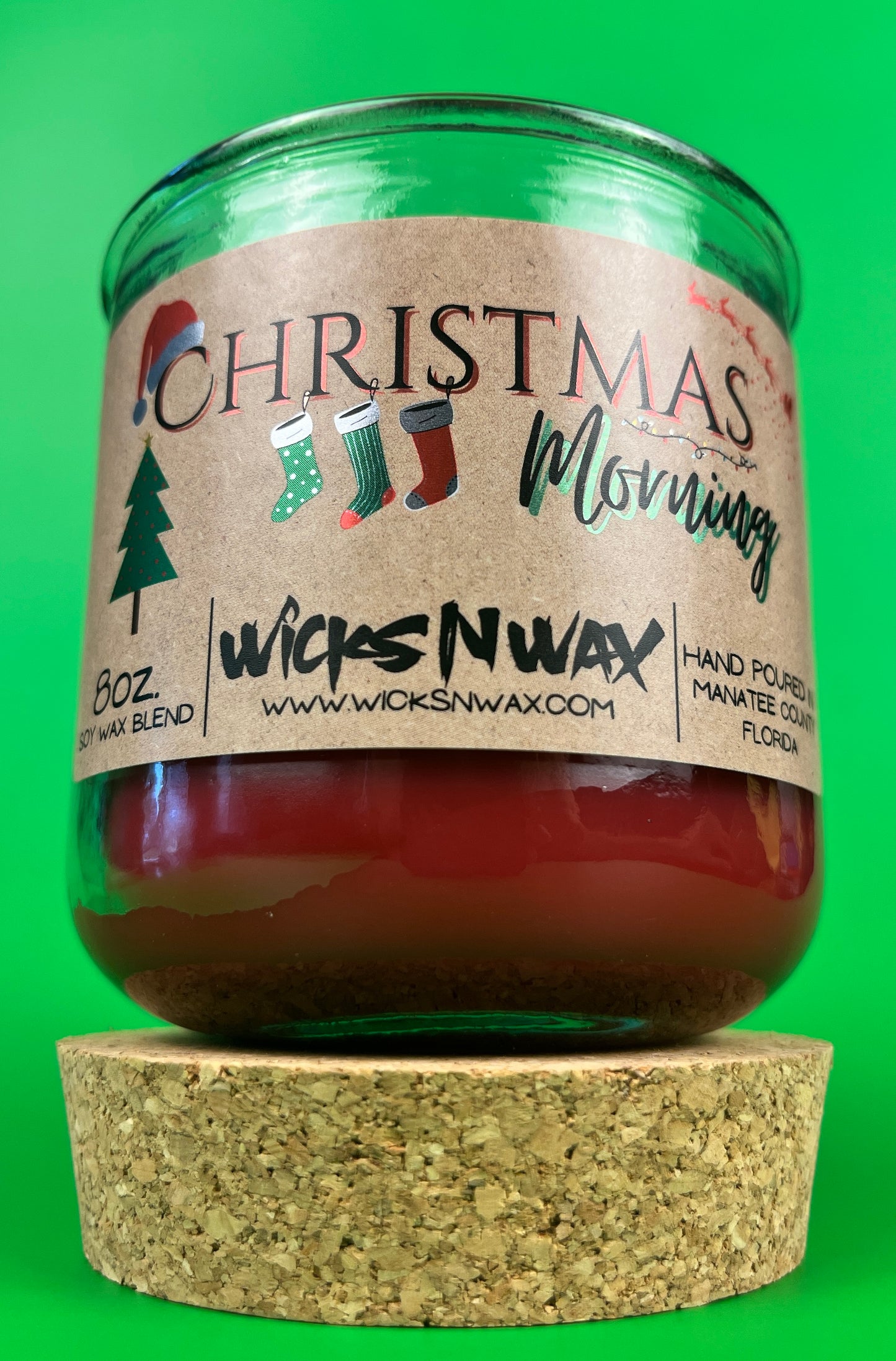 Christmas Morning recycled glass candle with side label and green jar, shown on cork base