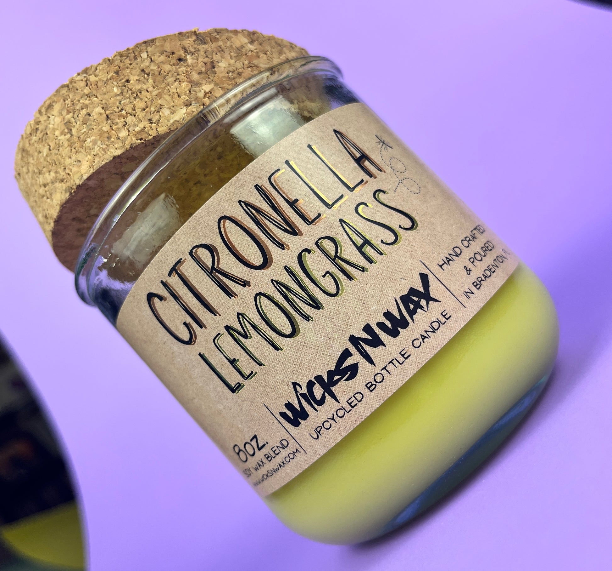 Recycled glass candle with green wax and “Citronella Lemongrass” label, angled view