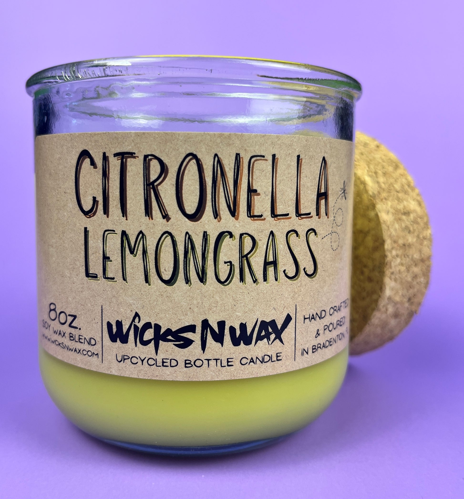 Recycled glass candle with green wax and “Citronella Lemongrass” label on front
