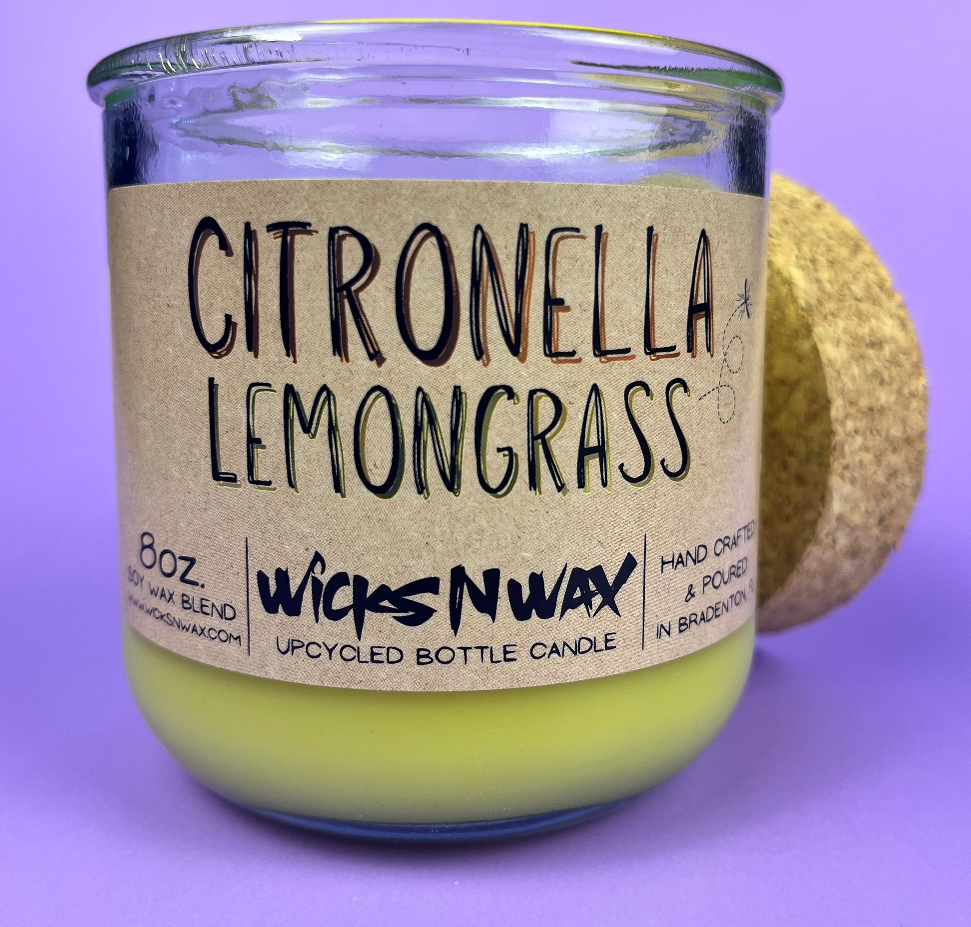 Recycled glass candle with green wax and “Citronella Lemongrass” label, side view
