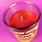 Recycled glass bottle candle with clear rim and magenta wax, lit wick visible
