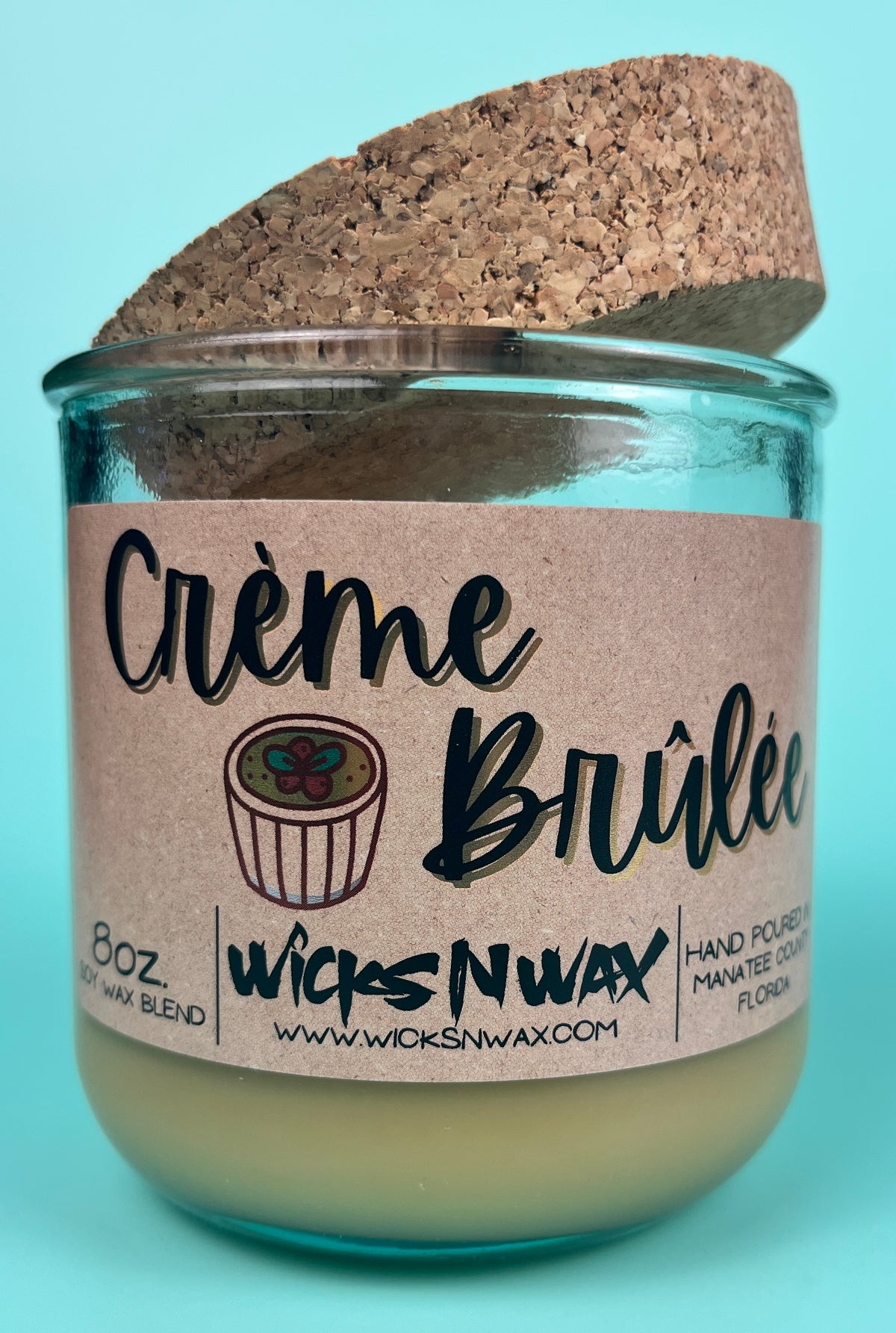 Recycled glass candle with kraft label and creamy wax; cork lid visible