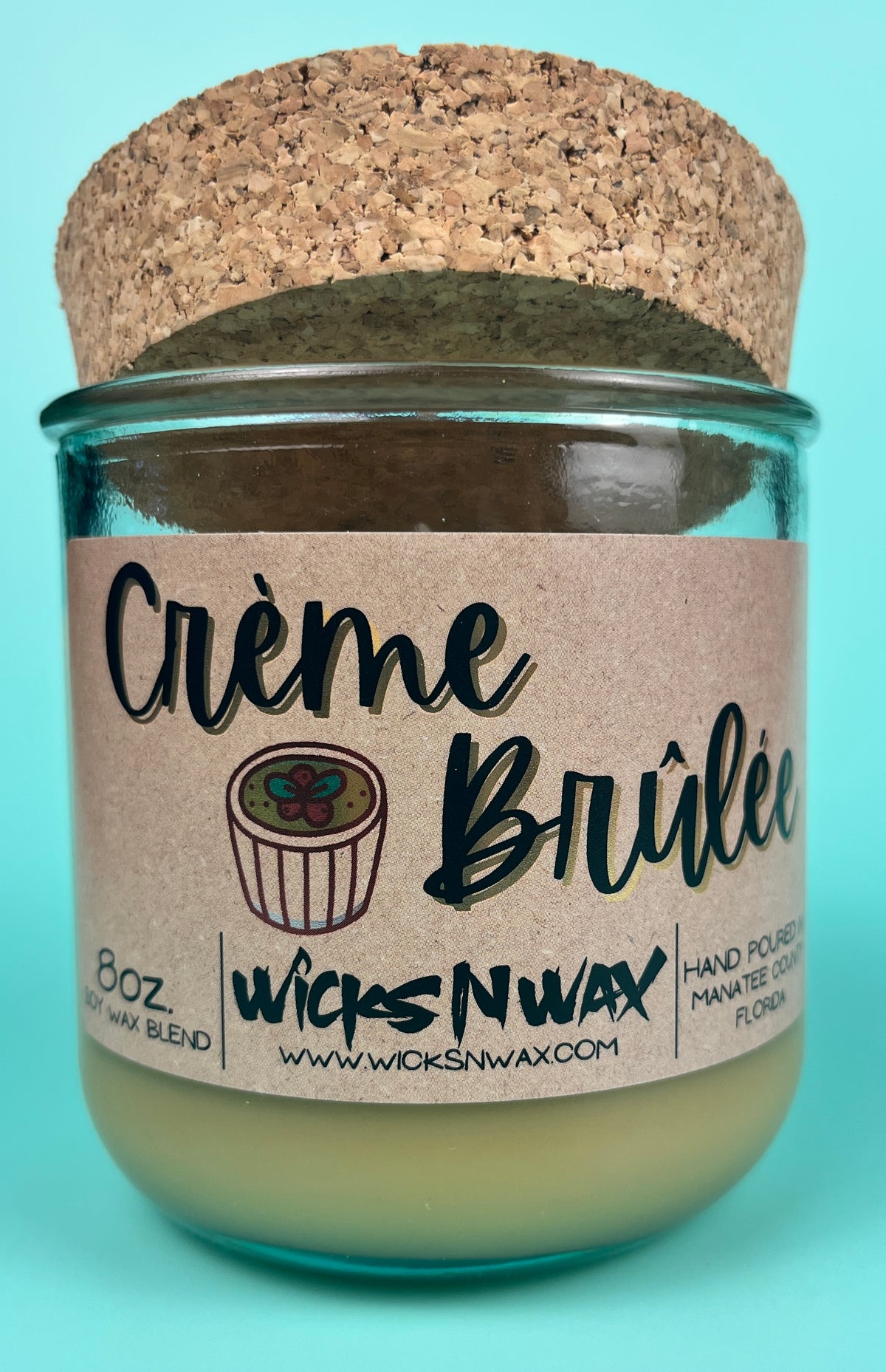 Recycled glass candle with creamy wax, kraft label, and cork lid covering the top