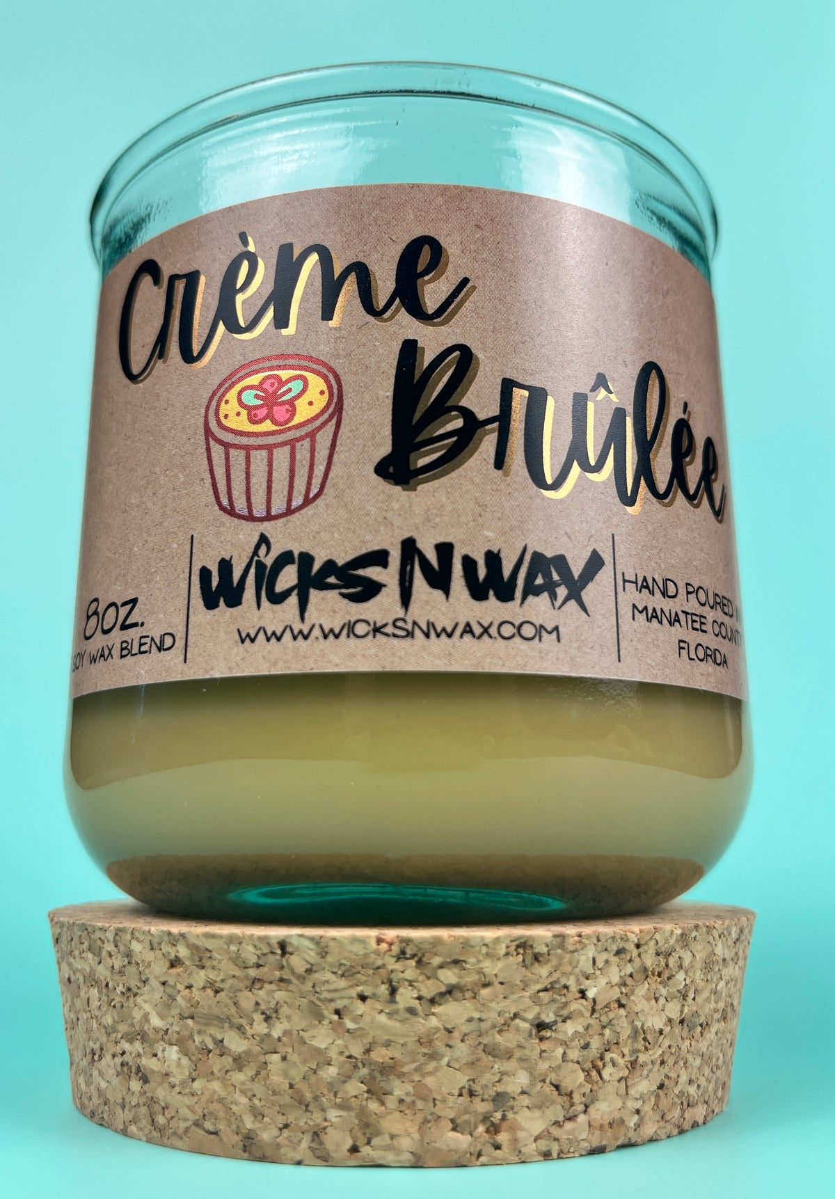 Recycled glass candle with creamy wax on cork base; kraft label shows WicksNWax and Creme Brûlée