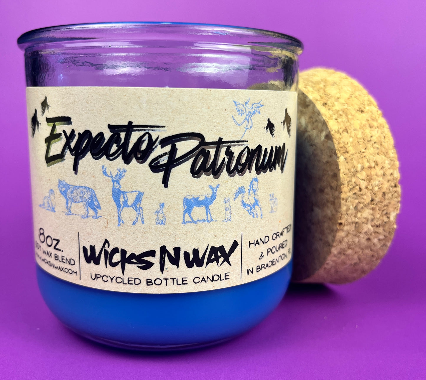 Blue glass candle jar with cream label, black illustration, and cork base ring