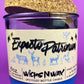 Blue glass candle jar with cream label, cork lid behind it, and illustrated figures
