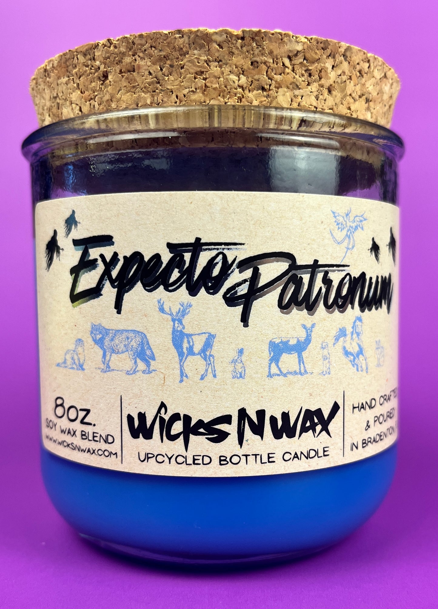 Blue glass candle jar with cream label and illustrated figures, cork base and label visible