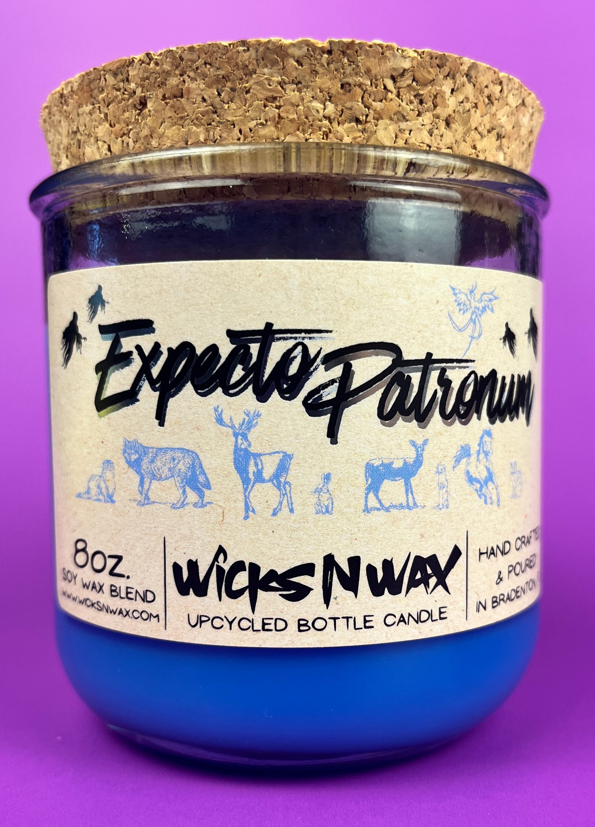 Blue glass candle jar with cream label and illustrated figures, cork base and label visible