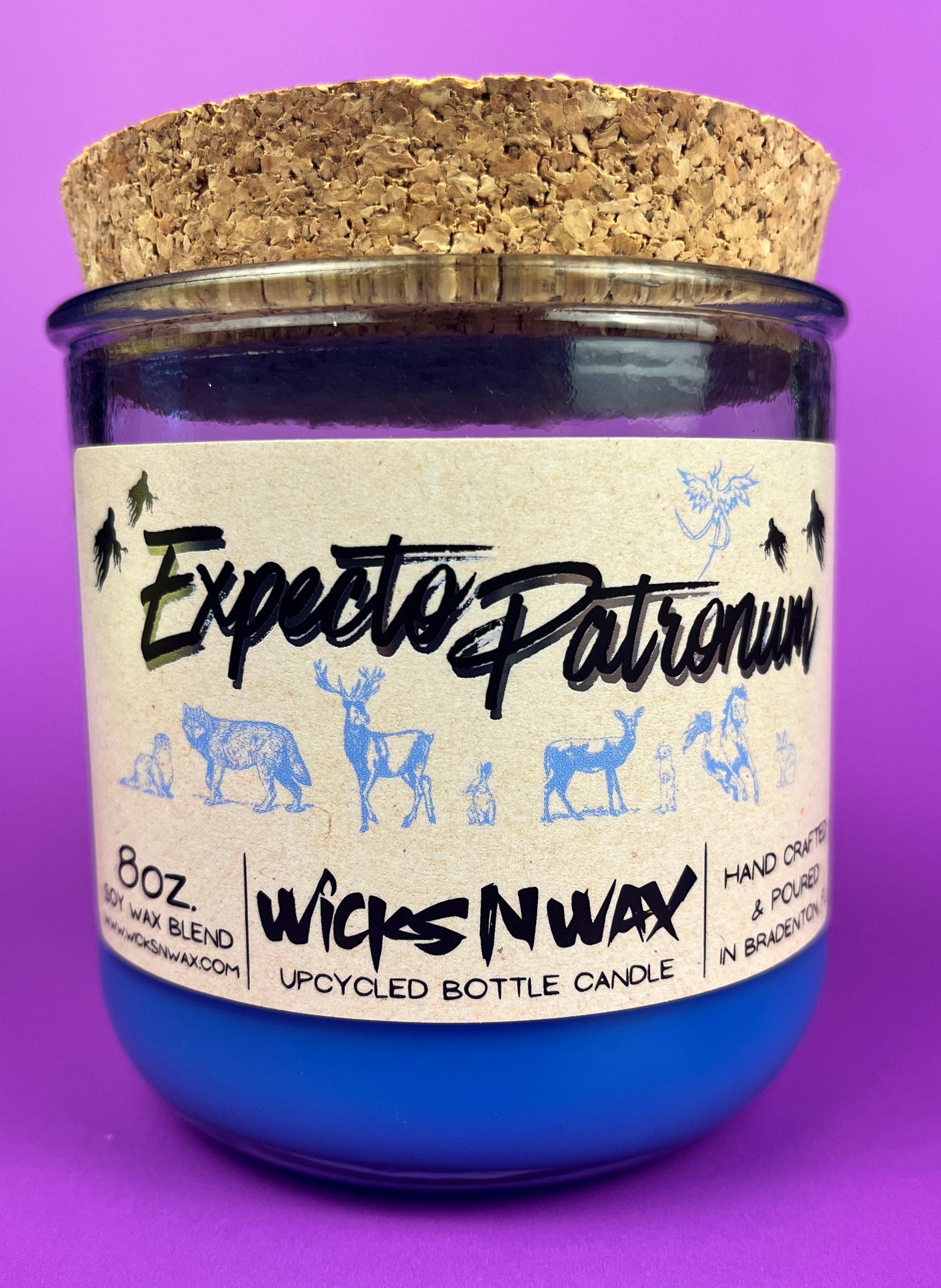 Blue glass candle jar with cream label and illustrated figures, cork lid behind