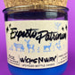 Blue glass candle jar with cream label and illustrated figures, shown with cork base