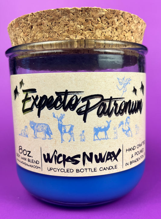 Blue glass candle jar with cream label and illustrated figures, shown with cork base