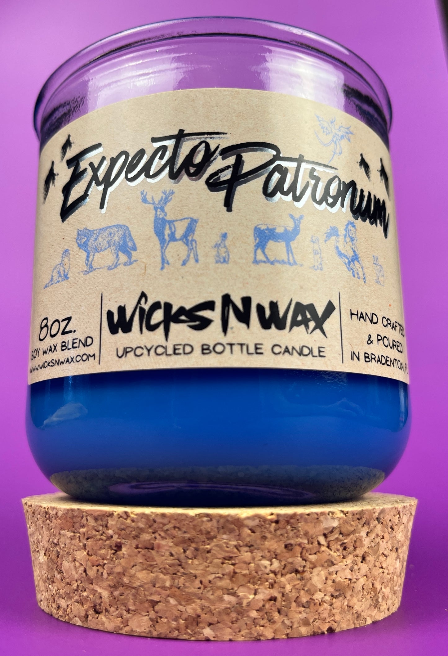 Blue glass candle jar with cream label and illustrated figures, cork base at bottom