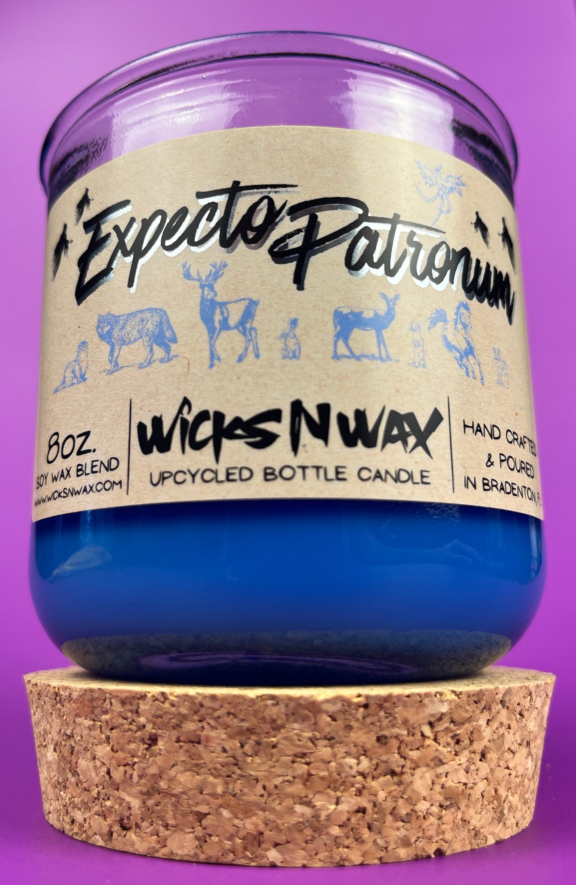 Blue glass candle jar with cream label and illustrated figures, cork base visible