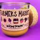 Glass candle jar angled view with Farmers Market label and cork lid, amber wax