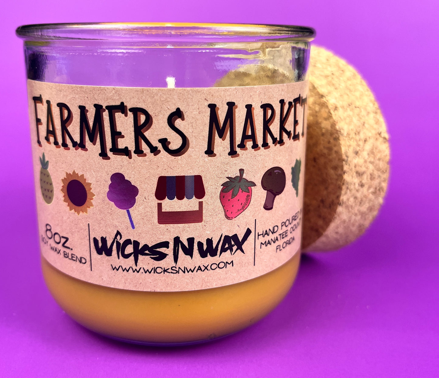 Glass candle jar angled view with Farmers Market label and cork lid, amber wax