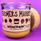 Glass candle jar angled with Farmers Market label, amber wax and cork base behind