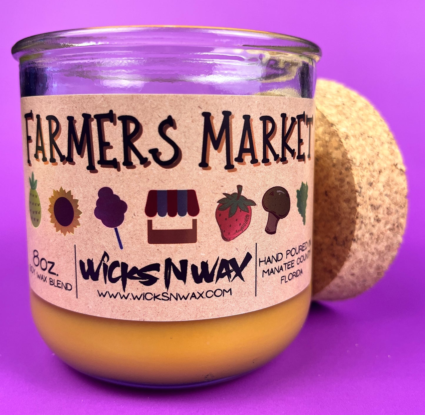 Glass candle jar angled with Farmers Market label, amber wax and cork base behind
