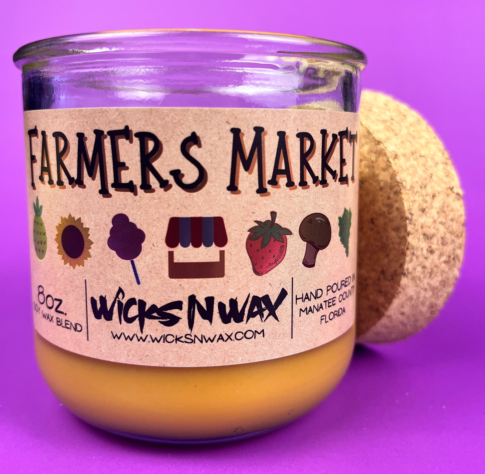 Glass candle jar angled with Farmers Market label, amber wax and cork base behind