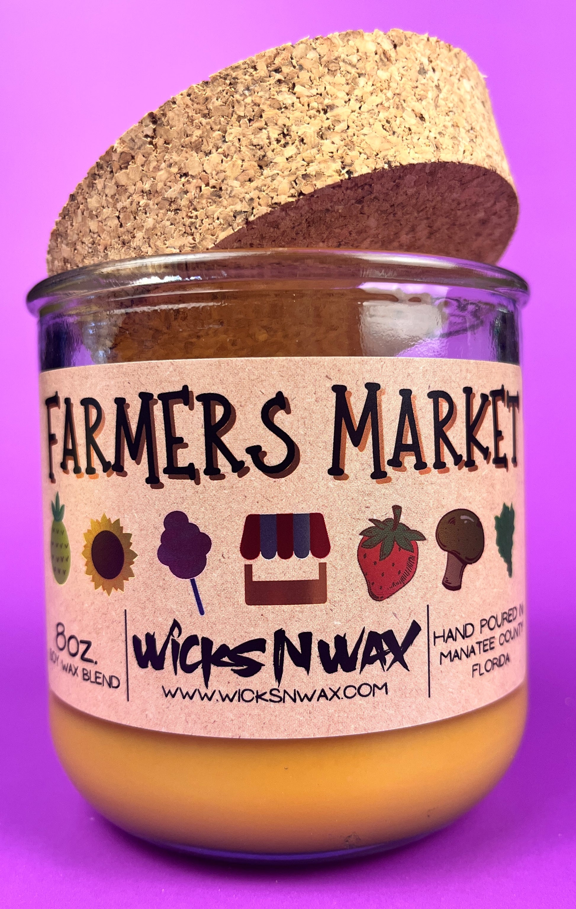 Glass candle jar with Farmers Market label and cork lid, amber wax surface visible