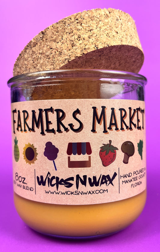 Glass candle jar with Farmers Market label and cork lid, amber wax surface visible