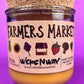 Glass candle jar with Farmers Market label and cork lid, amber wax fill visible