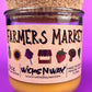 Glass candle jar showing Farmers Market label and amber wax fill, cork lid on top