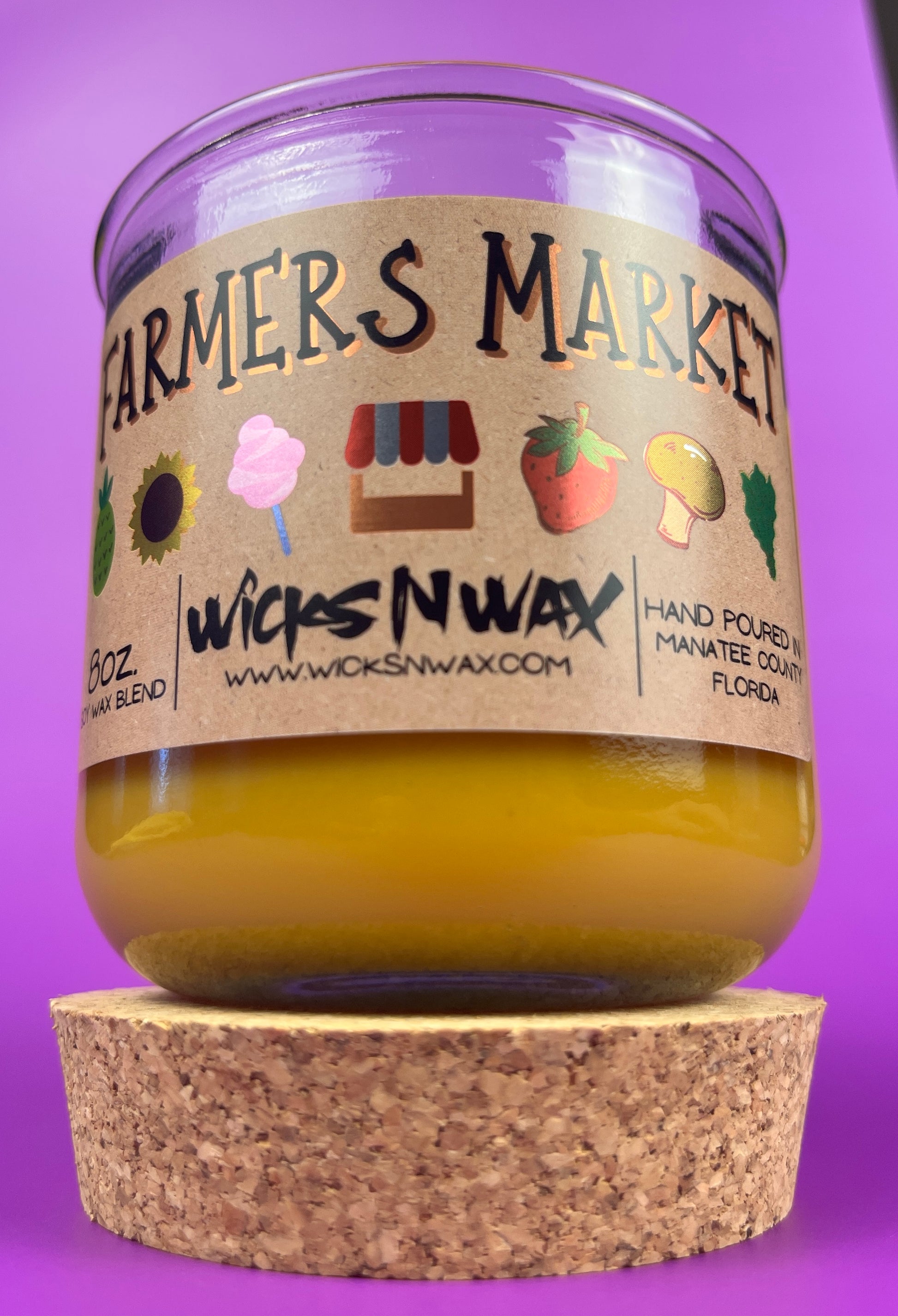 Glass candle jar with Farmers Market label and amber wax, cork base at bottom