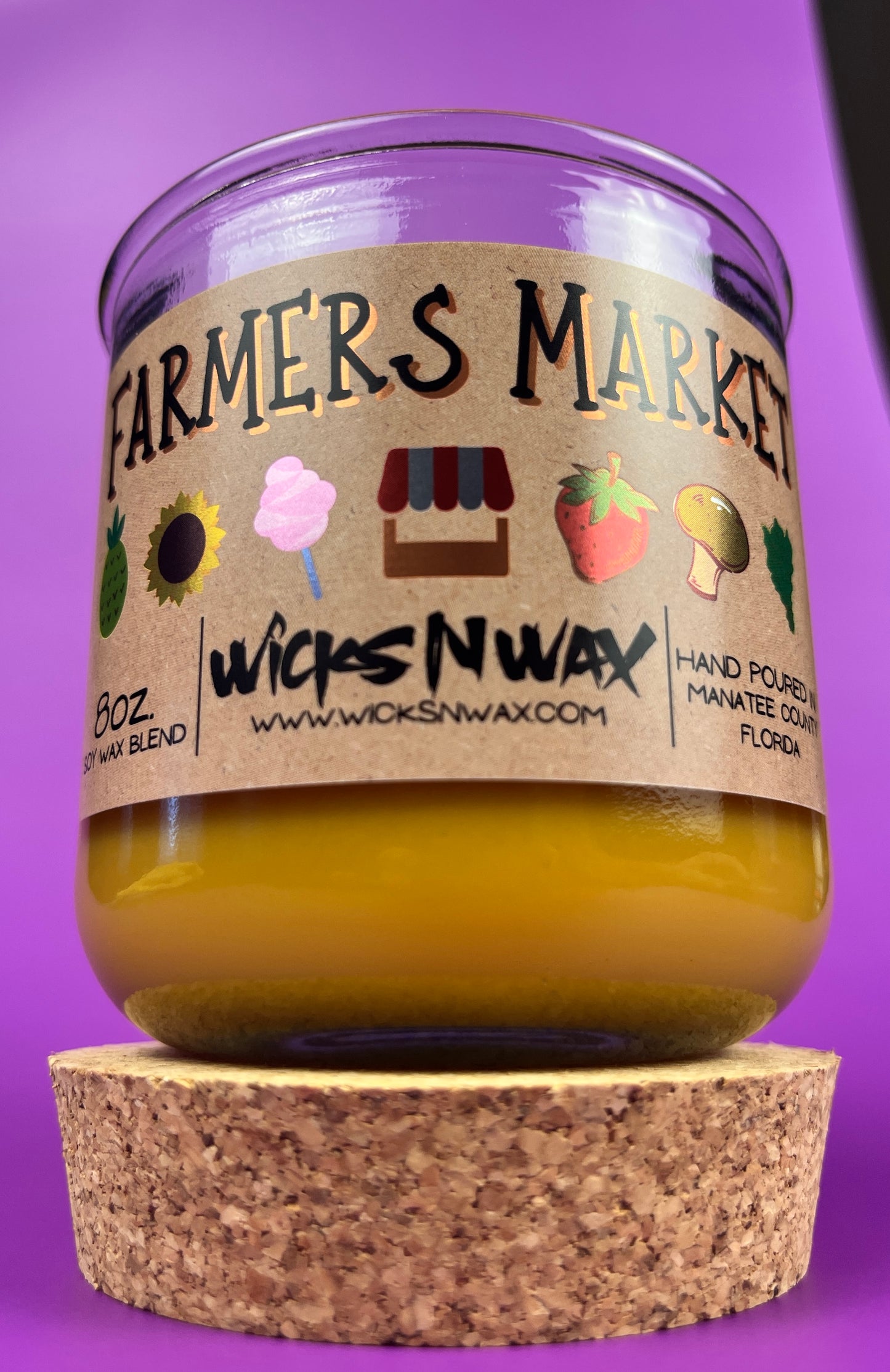 Glass candle jar with Farmers Market label, amber wax pool and cork base visible