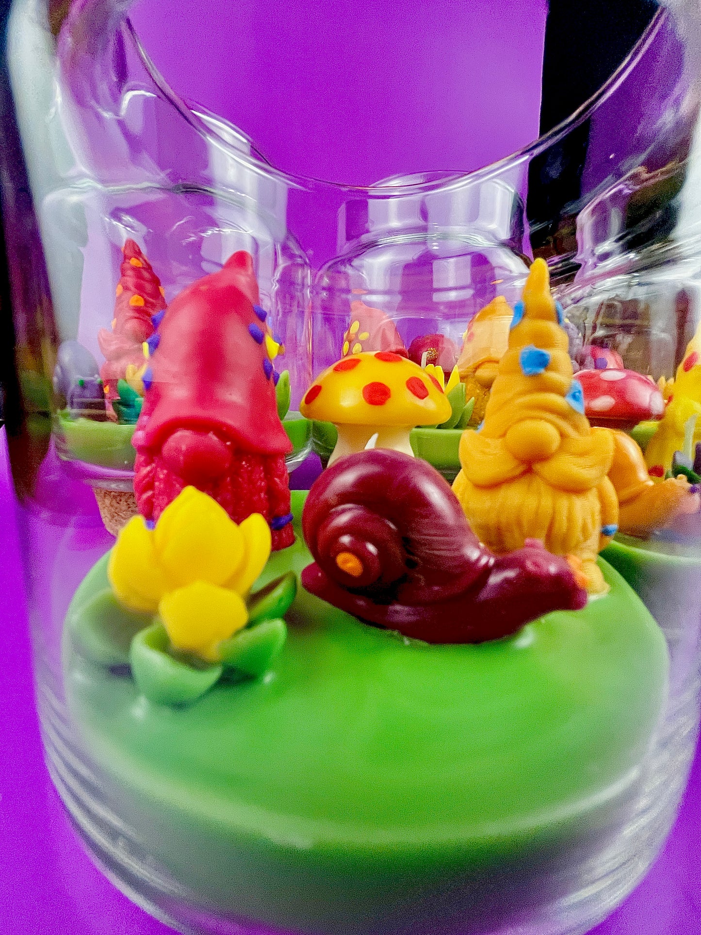 Garden gnome art candle jar with green wax base and red gnome, yellow cone, and purple accents