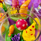 Garden gnome art candle jar with green wax base and purple flowers, red dots, and yellow shapes