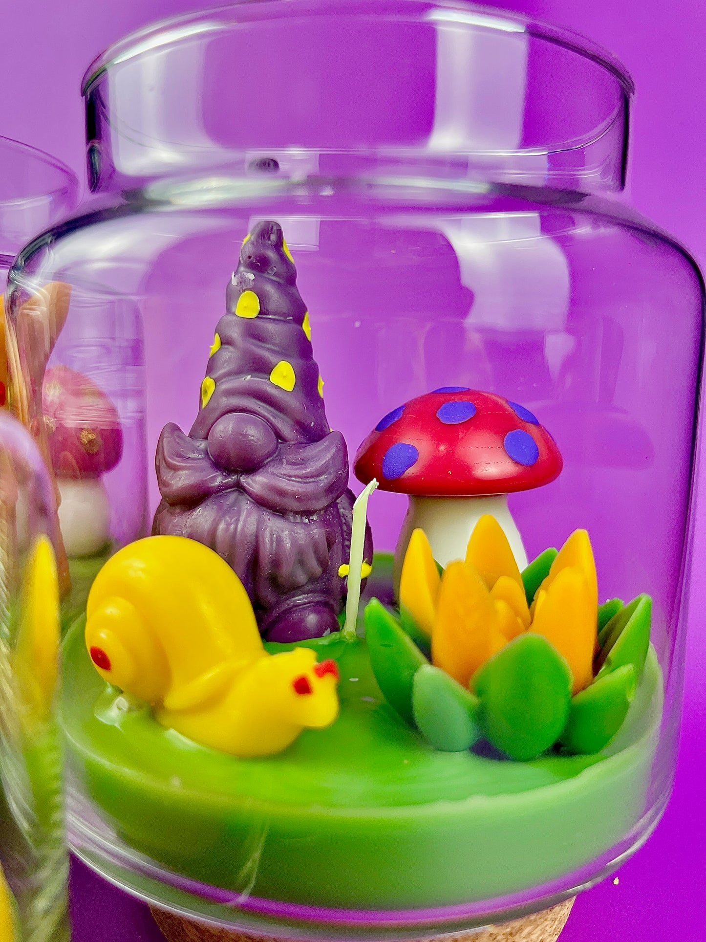 Garden gnome art candle jar with green wax base and purple, yellow, red gnome figures