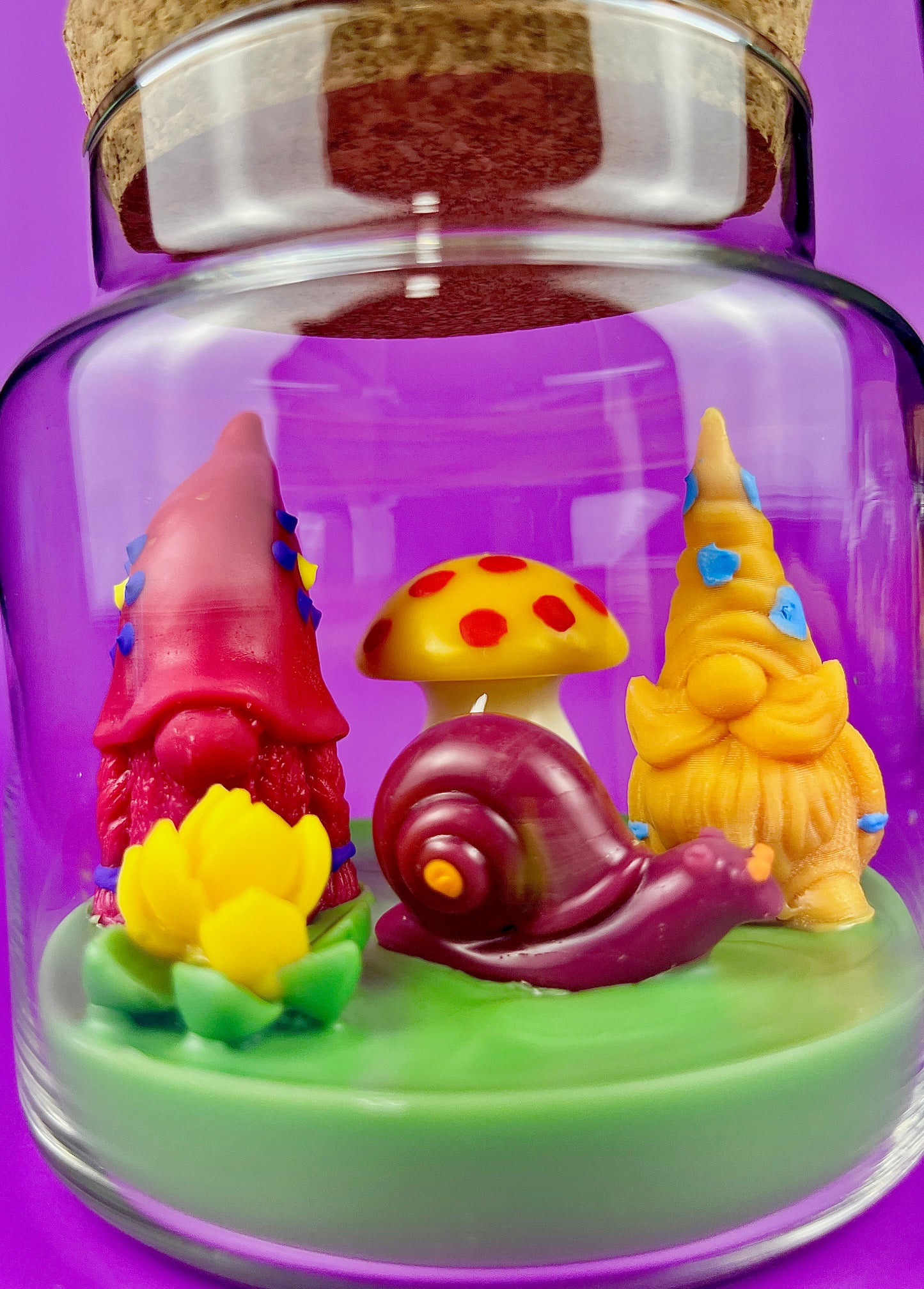 Garden gnome art candle in clear jar with green wax and gnome, mushroom, and flower figurines