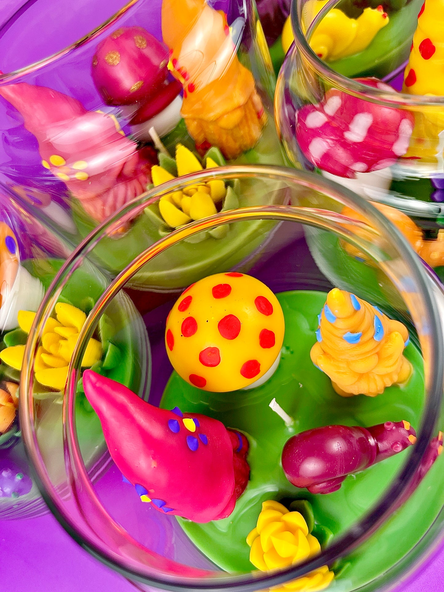 Garden gnome art candle in clear jar with colorful wax shapes on green wax base