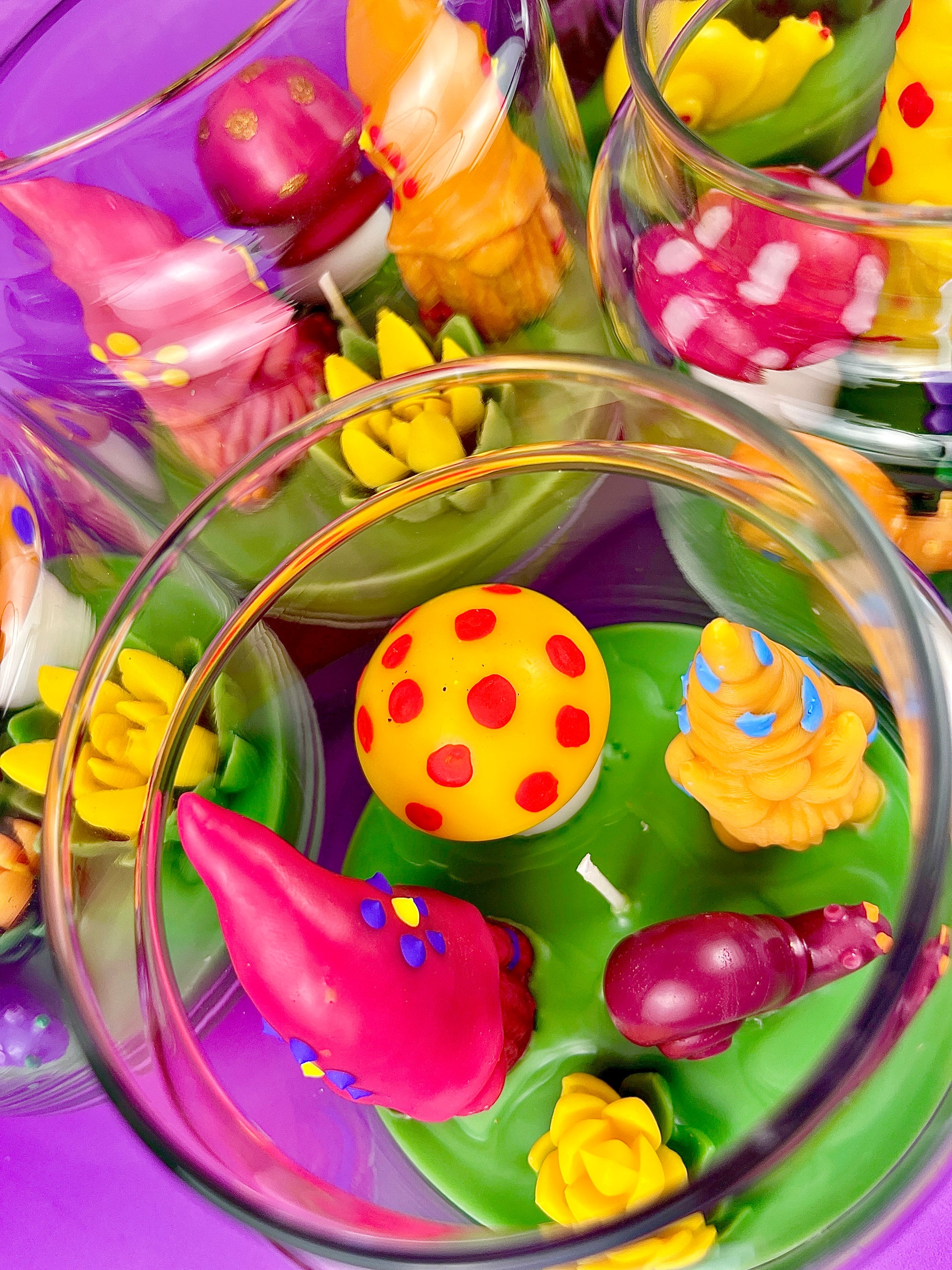 Garden gnome art candle in clear jar with colorful wax shapes on green wax base