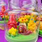 Garden gnome candle: red gnome, yellow figures, snail and green wax base