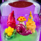 Garden gnome art candle jar with green wax base and red, yellow, and purple gnome figures