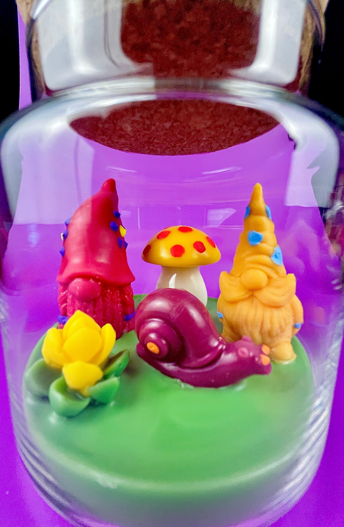 Garden gnome art candle jar with green wax base and red, yellow, and purple gnome figures