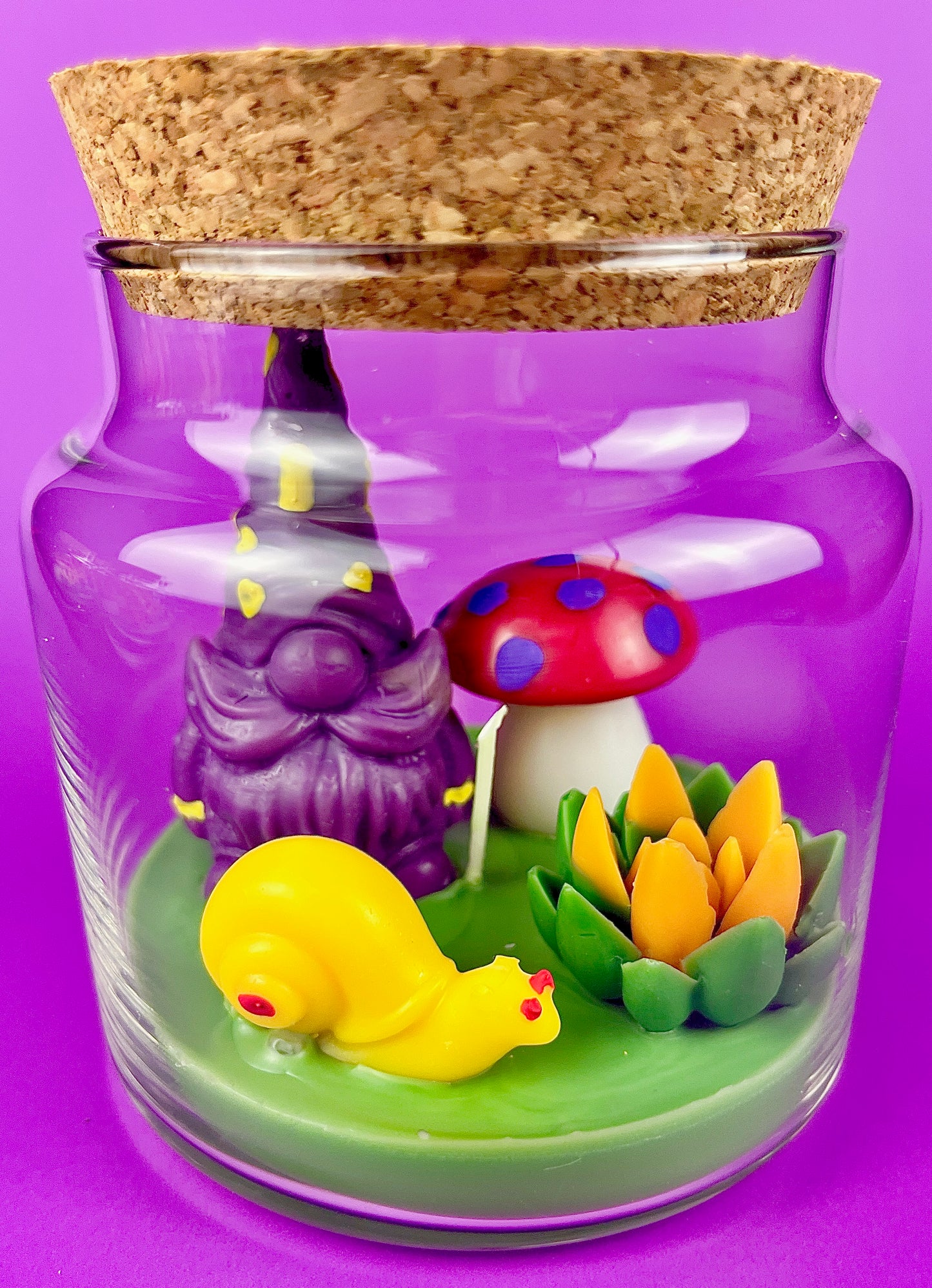 Garden gnome art candle in clear glass jar with purple gnome, mushrooms, and flower figurines