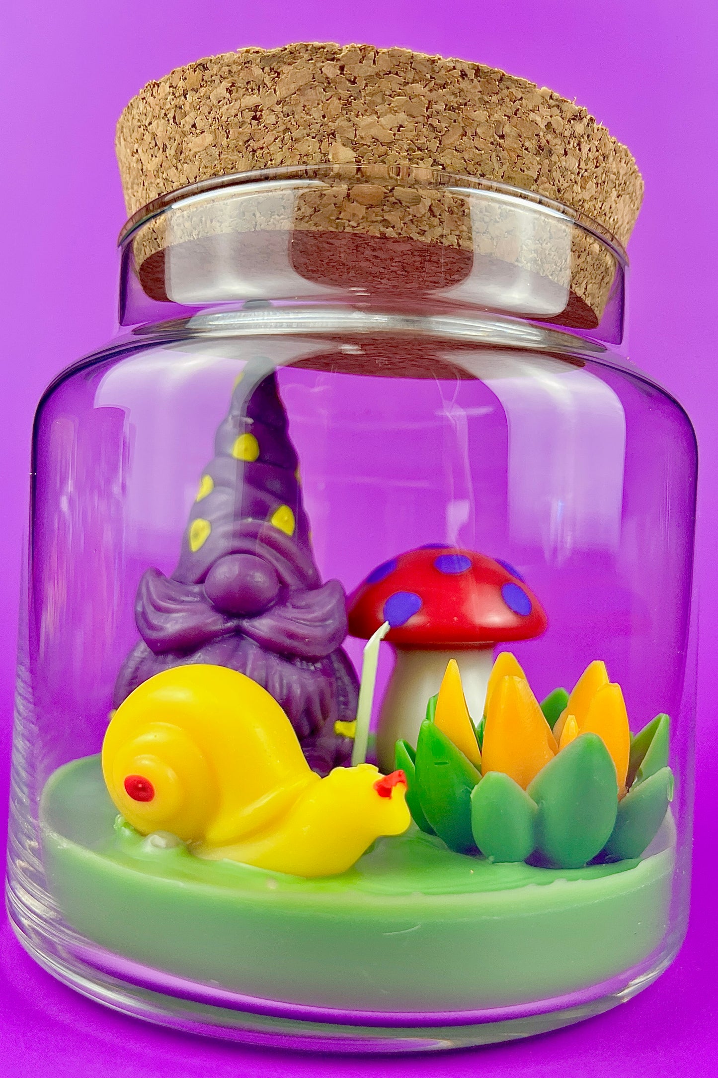 Garden gnome art candle in clear glass jar with yellow gnome, purple gnome, and garden flowers