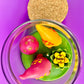 Garden gnome art candle in clear glass jar with green wax and pink mushroom and flower figurines