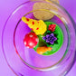 Garden gnome art candle in clear glass jar with green wax and yellow gnome and rose figurines