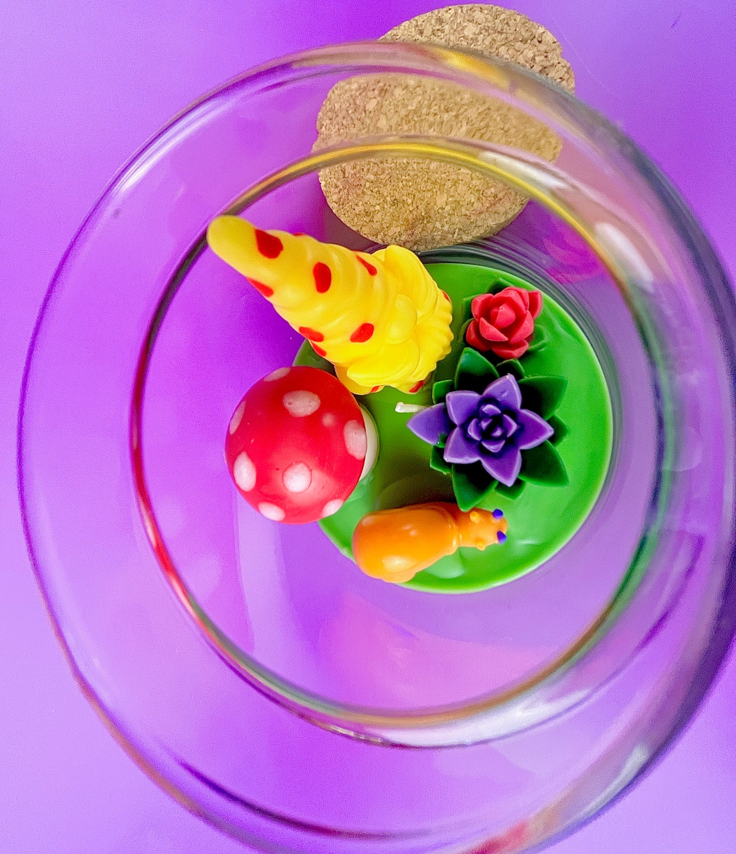 Garden gnome art candle in clear glass jar with green wax and yellow gnome and rose figurines