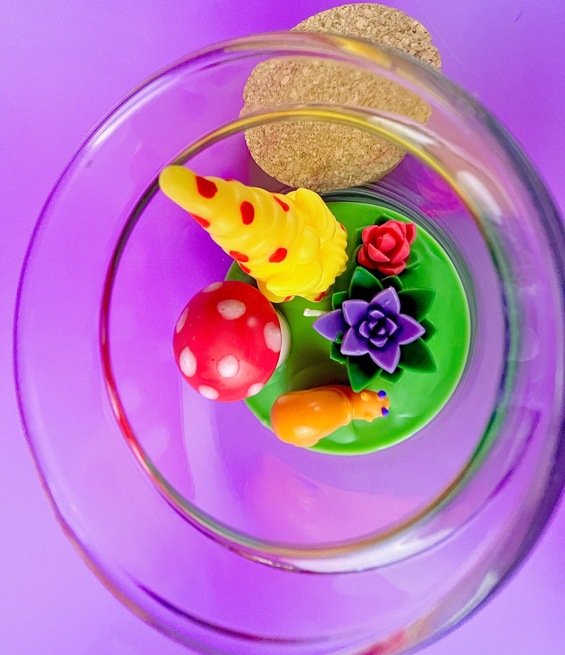 Garden gnome art candle in clear glass jar with green wax and yellow gnome and rose figurines