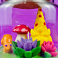 Garden gnome art candle in clear glass jar with yellow gnome, red mushroom, and flowers